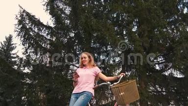 姜红头女孩坐在自行车上，在夏<strong>季</strong>公园的智能手机上发短信。 穿着<strong>粉色</strong>衬衫和牛仔裤