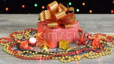 漂亮的圣诞礼品盒，上面有红色和金色条纹的蝴蝶结，木地板上有装饰，五颜六色的闪光