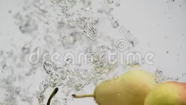 成熟的水果红黄梨落入水中，溅起水花和泡泡
