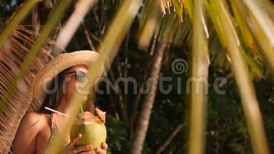 在热带海滩喝新鲜泰国椰子水的年轻有魅力的混合种族<strong>旅游</strong>女孩。 4K，慢动作。 <strong>普吉岛</strong>