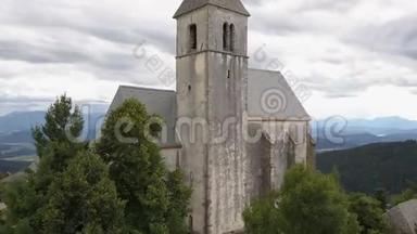 在山上的古教堂上空飞行。 奥地利卡林西亚马格达伦斯堡的真实景色。 美丽的山脉