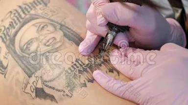 纹身大师迷人的女人与可怕的纹身客户的女孩在臀部。 黑色纹身机和墨水