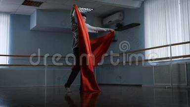 排练厅的年轻人.. 排练跳舞作为陈述。 他用<strong>红色布</strong>料做旋转。 织物