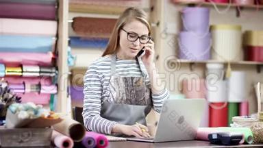 花店女花店女花匠在手机上聊天的同时使用笔记本电脑，在线查看<strong>订单</strong>.. 批发花卉<strong>销售</strong>
