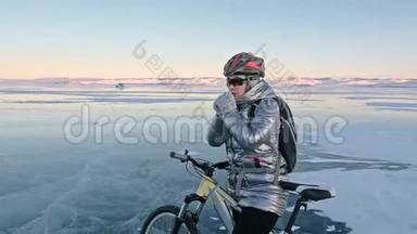 女人在冰上骑自行车。 女孩穿着银色羽绒服，自行车背包和头盔。 女人是
