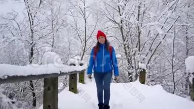 女人沿着一条小路走在美丽的冬天白雪覆盖的风景中。 晴朗的晴朗的霜冻天气。