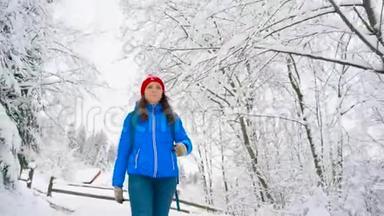 女人沿着一条小路走在美丽的冬天白雪覆盖的风景中。 晴朗晴朗的霜冻天气