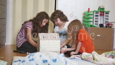 可爱的小女孩在玩玩具。 孩子们用手在室内制作了纸盒娃娃屋