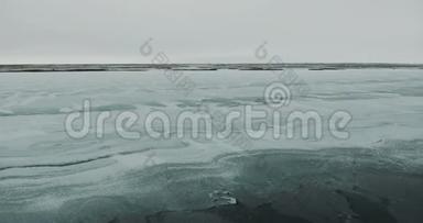 飞过湖面。冰封的湖面覆盖着厚厚的一层冰雪