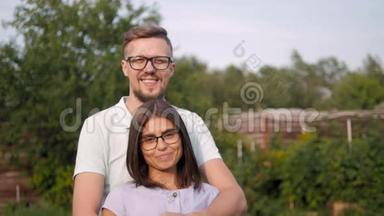 花园里一对恩爱幸福的年轻夫妇的画像，男人拥抱妻子