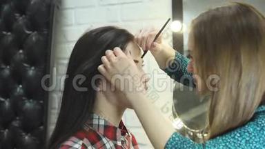 一位年轻的女化妆师在美容院做美容，美丽的黑发女孩