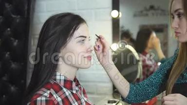 一位年轻的女化妆师在美容院做美容，美丽的黑发女孩