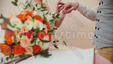 美丽的新娘和英俊的新郎在婚礼花束前戴着金戒指。 结婚仪式。