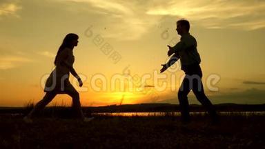 快乐的男人和女孩在夏天公园的晚上跳华尔兹。 爱的男人和女人在灿烂的阳光下跳舞