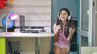 少女在音乐耳机里跳舞唱歌.. 女生在网上听音乐，在室内跳舞，唱歌