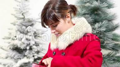 圣诞妇女打开袋子，礼物和惊喜的微笑，背景树