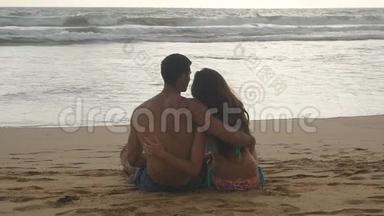 年轻的浪漫夫妇正在享受美丽的景色，<strong>坐</strong>在海滩上，晚上<strong>拥</strong>抱。 一个女人一个男人<strong>坐</strong>着