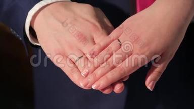新婚夫妇`手里拿着结婚戒指。 新娘和新郎带着结婚戒指。 结婚花束上的手和戒指
