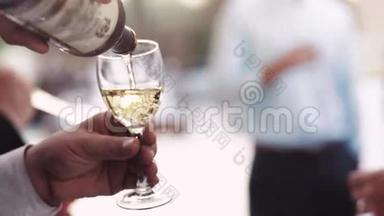 玛娜€™手把白葡萄酒倒进酒杯里。 婚礼派对，意大利婚礼。 近景，慢动作.. 户外活动