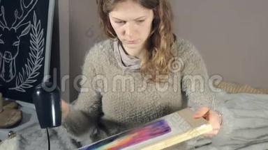 成年妇女用彩色水彩颜料作画，在艺术学校用吹风机吹干