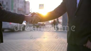两位商务男士在城市背景模糊的情况下握手