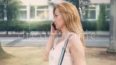 快乐的年轻女子在电话里交谈，在炎热的阳光明媚的夏日沿着海滨散步。 4k，慢动作