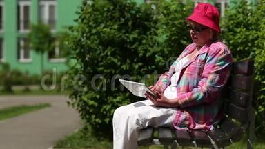 带着平板电脑的女人坐在长凳上，用手机说话