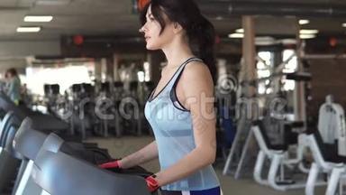 年轻女子在健身房的跑步机上行走。 健身房的有氧运动