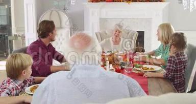 一家人围坐在餐桌旁吃感恩节大餐-祖母在开始吃饭前做简短的演讲