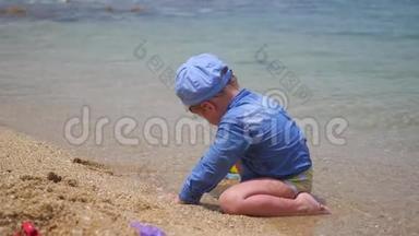 一个孩子在阳光明媚的热天在海滩上玩沙子和玩具