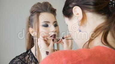 专业化妆师将化妆应用于美丽的模特。 红色口红的颜色。