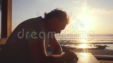 在海滩上的酒吧休息的帅哥在美丽的日落时分使用手机。慢动作。1920x1080个