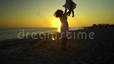 日落时分，年轻漂亮的女人和她的<strong>小</strong>女儿在海滨散步。 妈妈把女儿抱在怀里。 他们