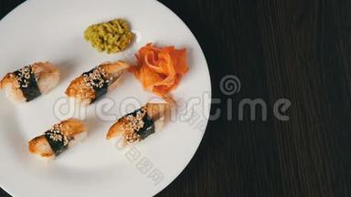 一个白色的<strong>大盘</strong>子，上面放着四个巨大的寿司，鳗鱼在粉红色的生姜和绿色的旁边倒着一块诺丽
