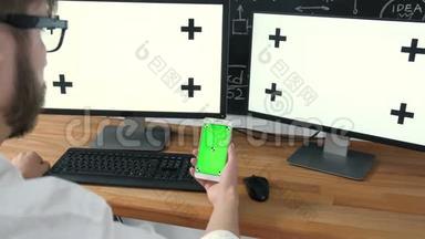 男人拿着平板电脑和手表电视绿色屏幕。 男人手里拿着手机绿屏看电视