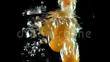 许多橙色的昆曲<strong>落入水中</strong>的超级慢动作视频。 黑色背景