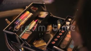 化妆师从她的手提箱里拿出化妆品。 专业化妆品化妆师在行李箱里.. 多元色