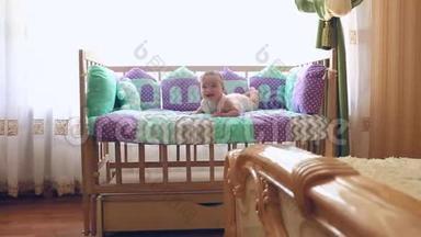 美丽快乐的小女孩趴在婴儿床上笑