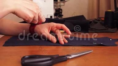 裁缝裁剪布料. 女孩用剪刀剪布料。 织物上的刺针。