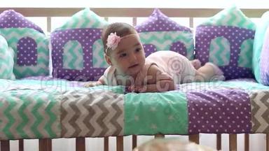 美丽快乐的小女孩趴在婴儿床上笑