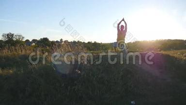 日落时分，年轻人在山上练习瑜伽动作和姿势。 在大自然中站在瑜伽姿势的运动男。 美丽美丽