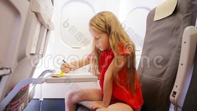 可爱的小女孩坐飞机坐飞机窗。 孩子用彩色铅笔画图片。