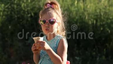 在阳光明媚的夏天，小女孩戴着太阳镜吃冰淇淋。