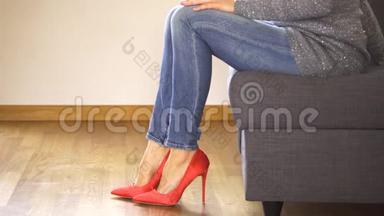 穿着<strong>红色高跟鞋</strong>坐在沙发上的女人展示和交叉，修长的腿