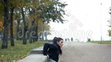 穿运动服装的女人的肖像，在秋季公园户外做健身俯卧撑锻炼。
