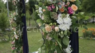 户外婚礼的婚礼装饰。 用白色和粉红色玫瑰装饰的木制拱门。 蜜蜂和大黄蜂
