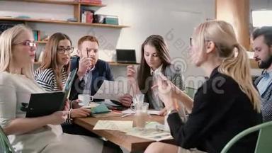 创意商业团队在一个现代化的创业办公室的桌子上。 女领导讲解项目细节..