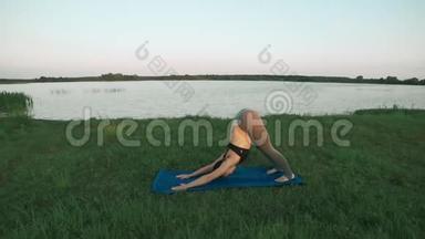美丽的年轻女子在日出时在蓝色的瑜伽垫上做瑜伽，安静的风景