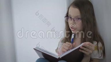 戴眼镜的漂亮小女孩勤奋地在窗口做作业。