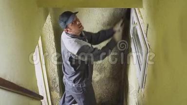 这个人用刷子和抹布擦干净墙壁上的坚固污垢。 工人手工清洗走廊墙壁.. 模具和